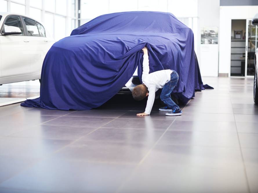 Boy at car dealer unveiling tarpaulin