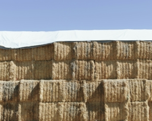 Tarpaulin covering stacked hay bales.